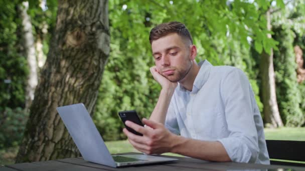 En ung Man använder en telefon i parken — Stockvideo