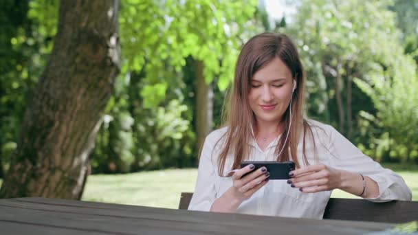 Jeune femme à l'écoute de la musique dans le parc — Video