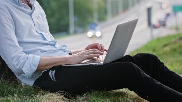 En ung man med en laptop utomhus — Stockvideo