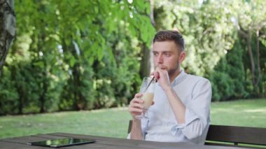 Genç bir adam parkta milkshake içme