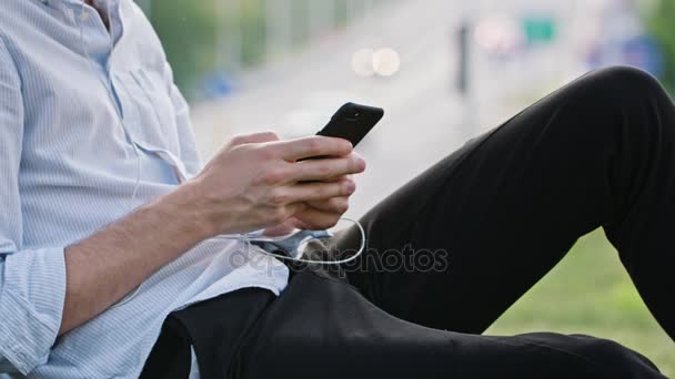 Un joven usando un móvil al aire libre — Vídeos de Stock