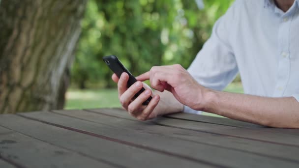 Manos de hombre usando un teléfono en el parque — Vídeos de Stock