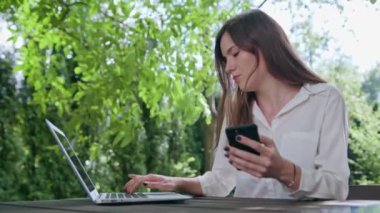 İş kadını bir dizüstü bilgisayar ve bir telefon kullanma