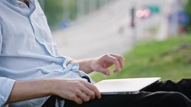 Ένας νεαρός άνδρας, χρησιμοποιώντας ένα φορητό υπολογιστή σε εξωτερικούς χώρους — Αρχείο Βίντεο