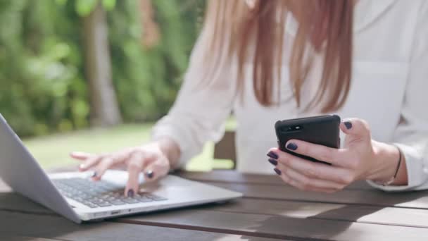 Företag dam använder en bärbar dator och en telefon — Stockvideo