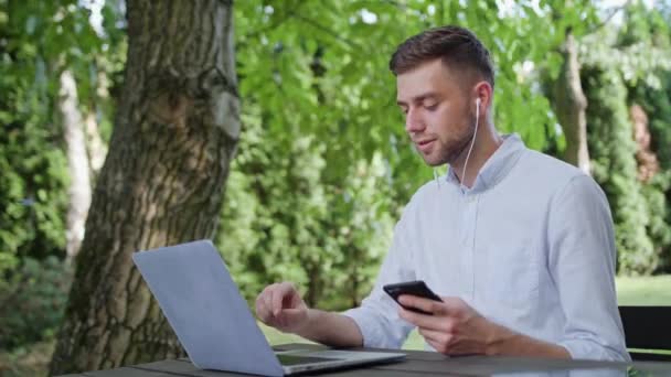 En ung Man pratar i telefon i parken — Stockvideo