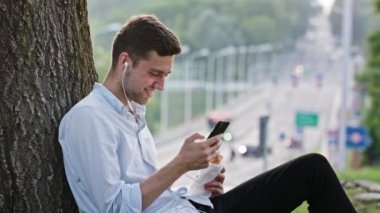Genç bir adam açık havada bir cep telefonu kullanarak