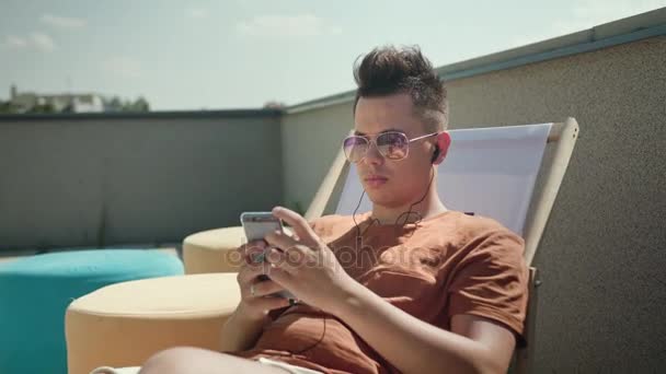 Un giovane che usa uno smartphone sulla terrazza . — Video Stock