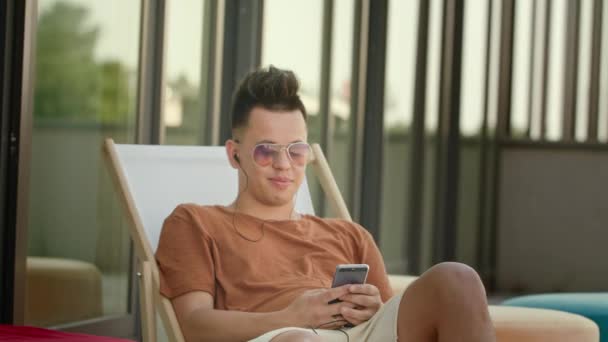 Um jovem usando um smartphone no terraço . — Vídeo de Stock