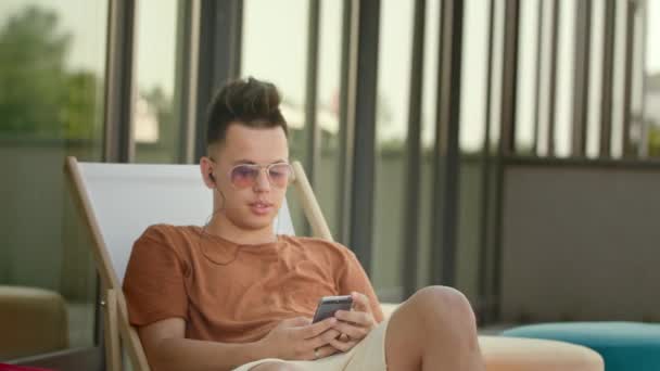 Молода людина використовує смартфон на терасі . — стокове відео