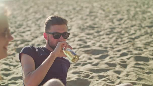 Hombre joven bebiendo cerveza en la playa — Vídeo de stock