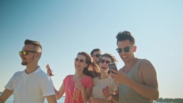 Jóvenes divirtiéndose en la playa usando teléfonos — Vídeos de Stock