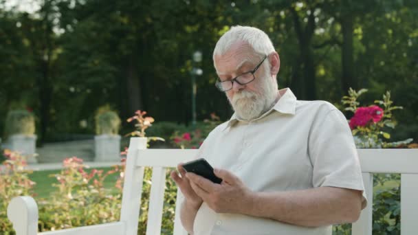 Gammal Man använder en telefon utomhus — Stockvideo