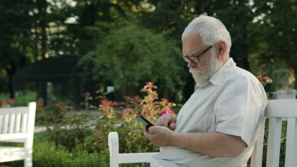 Viejo usando un teléfono al aire libre — Vídeos de Stock