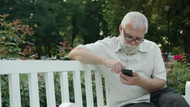 Viejo usando un teléfono al aire libre — Vídeo de stock