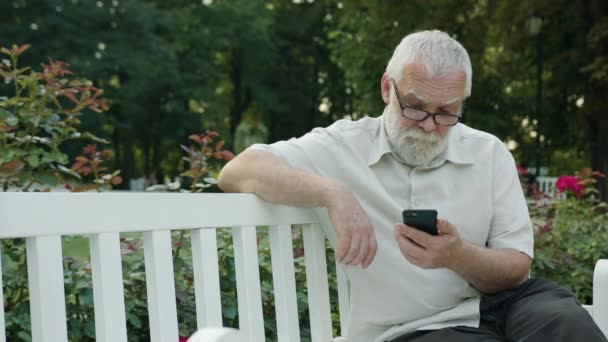 Vieil homme utilisant un téléphone à l'extérieur — Video