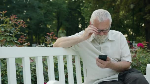 Старий користується телефоном на відкритому повітрі — стокове відео