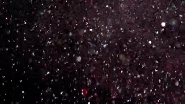 Paillettes réalistes explosant sur fond noir .