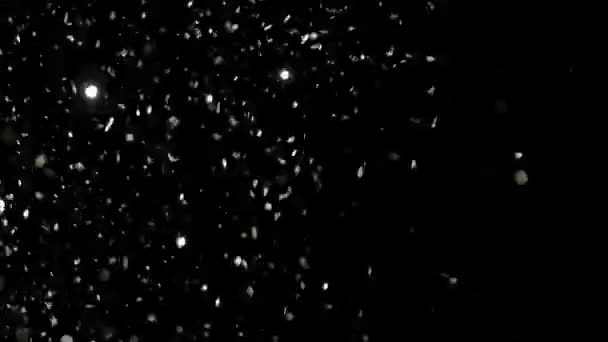 Paillettes réalistes explosant sur fond noir .