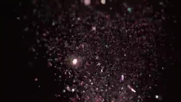 Paillettes réalistes explosant sur fond noir .