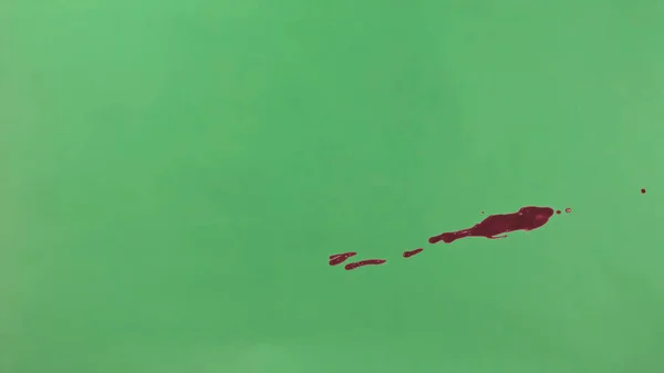 Red Ink Splatter Over Green Screen Background