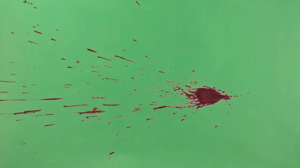 Red Ink Splatter Over Green Screen Background