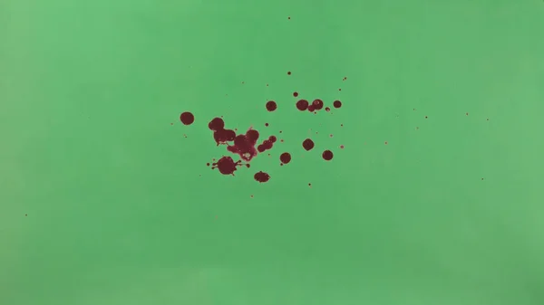 Red Ink Splatter Over Green Screen Background