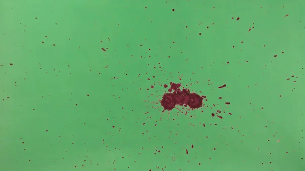 Red Ink Splatter Over Green Screen Background