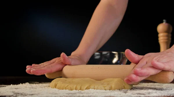 Manos femeninas extendiendo la masa sobre la mesa — Foto de Stock