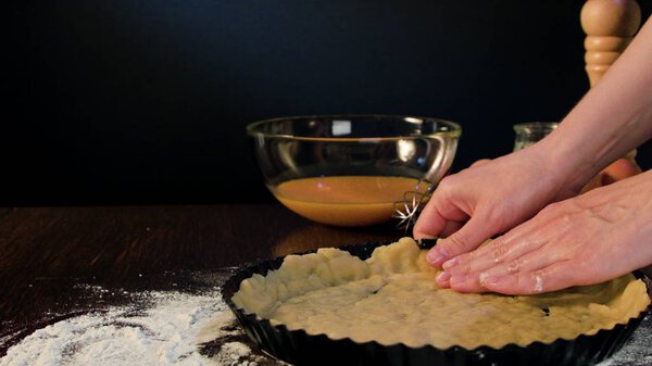 Женские руки покрывают тесто вокруг сковороды
