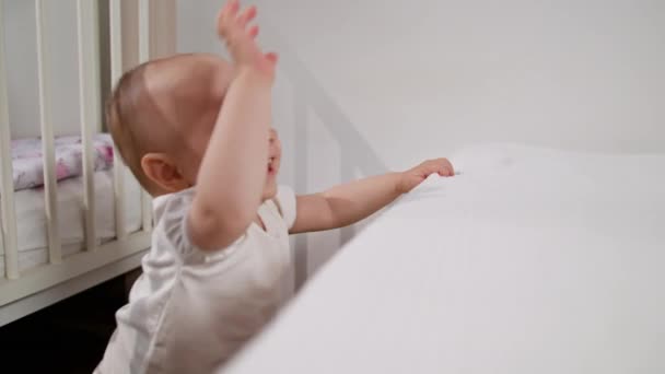 Bebé de pie cerca de la cama en casa — Vídeo de stock