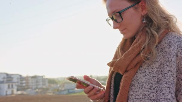 Une jeune femme utilisant un smartphone à l'extérieur — Video