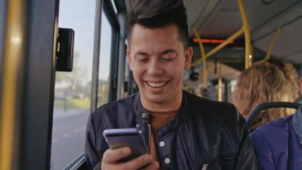 Un jeune homme utilisant un smartphone dans le bus — Video