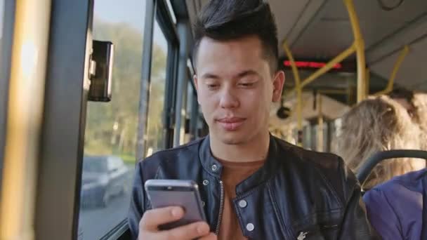 Um jovem usando um smartphone no ônibus — Vídeo de Stock