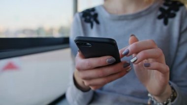 Otobüste akıllı telefon kullanan genç bir bayan.