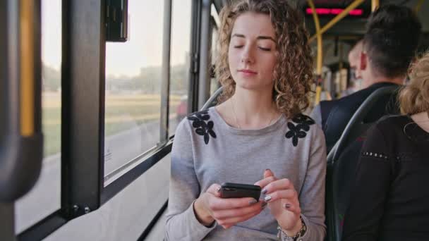 En ung dam som använder en smartphone på bussen — Stockvideo