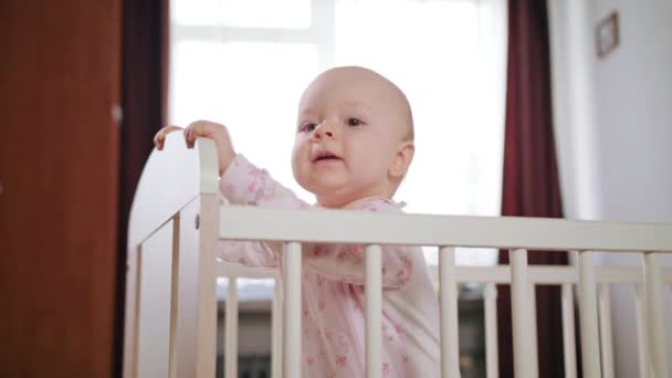 Младенец, стоящий в детской кроватке дома — стоковое видео