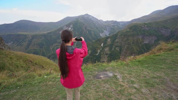 Eine junge Frau fotografiert in den Bergen. — Stockvideo