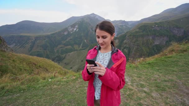 Una giovane signora che utilizza uno smartphone in montagna . — Video Stock