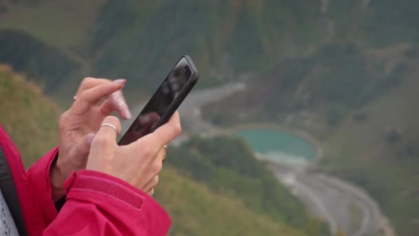 Uma jovem usando um telefone celular nas montanhas . — Vídeo de Stock