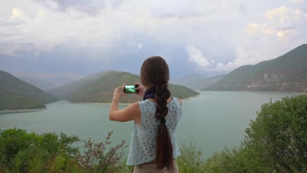 Una joven tomando fotos cerca del lago . — Vídeos de Stock