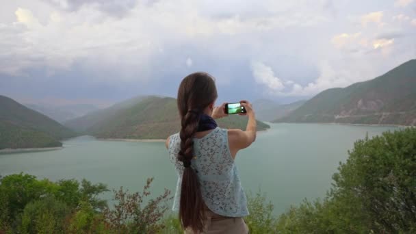 一位年轻的女士在湖边拍照. — 图库视频影像