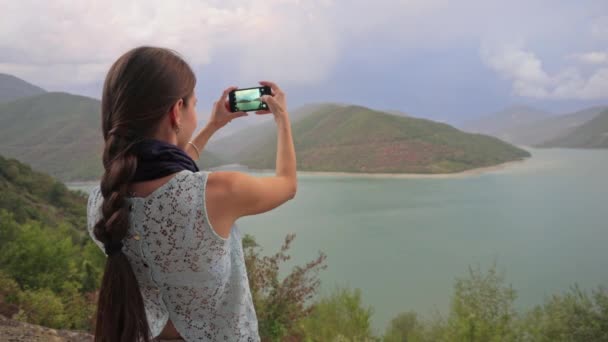 Una joven tomando fotos cerca del lago . — Vídeos de Stock