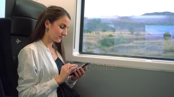 Egy fiatal hölgy egy okostelefon segítségével a vonaton. — Stock videók