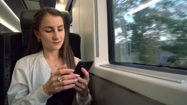 Una joven usando un teléfono inteligente en el tren . — Vídeos de Stock