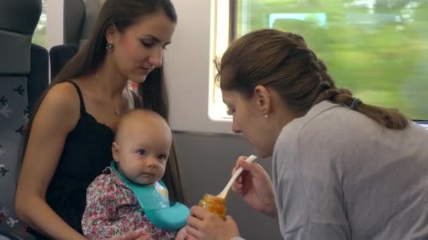 Dos señoritas alimentando a un bebé en el tren — Vídeos de Stock