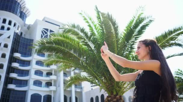 Een jonge dame met behulp van een Smartphone in de buurt van het Hotel. — Stockvideo