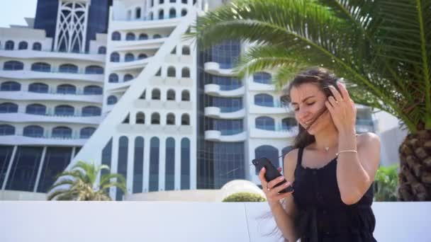 Uma jovem senhora usando um smartphone perto do hotel . — Vídeo de Stock