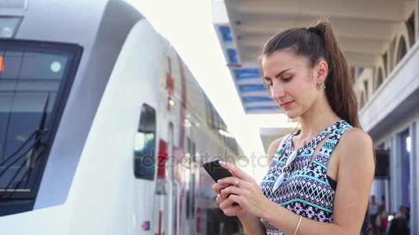Giovane signora Utilizzando uno smartphone alla stazione ferroviaria . — Video Stock