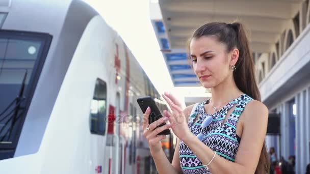 Joven dama usando un teléfono inteligente en Railwaystation . — Vídeos de Stock